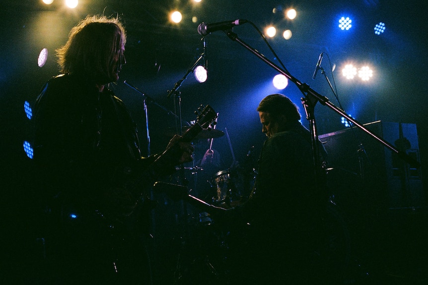 Ian Haug and John Collins performing on stage.