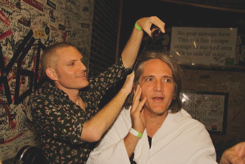 A man shaving another man's head.