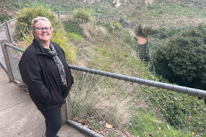 A woman standing at a fence around a cave entrance