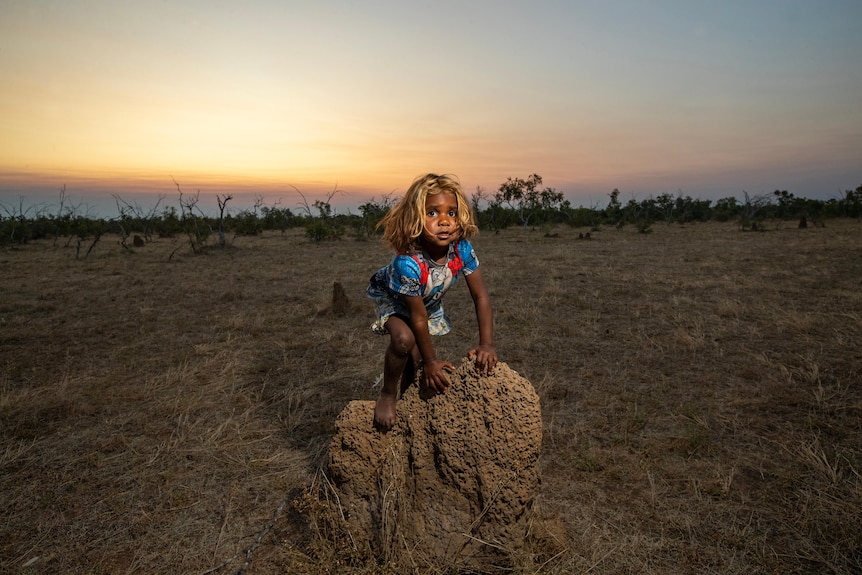 A young girl climbs upon an ant hill 