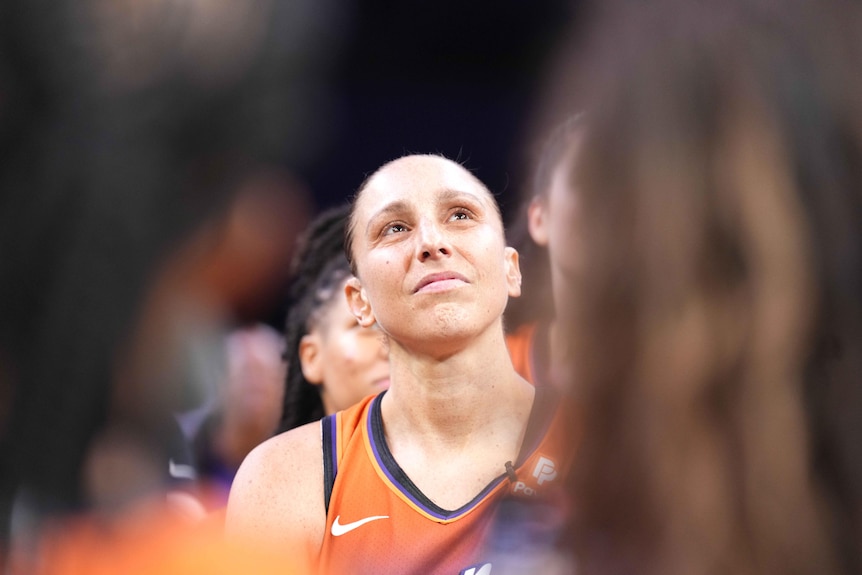 A woman in a orange jersey looks up 