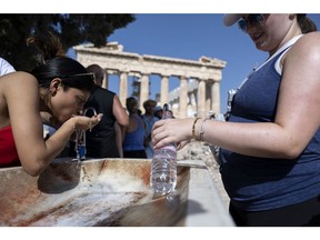 Tourists at a water fountain at the Acropolis archaeological site, during extreme hot weather conditions, in Athens in July 2023.  Photographer: Yorgos Karahalis/Bloomberg