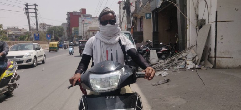 Govinda,27, wraps a white cloth (gamchha) around his face and wears sunglasses to protect himself from heat. Photograph by Parthu Venkatesh.