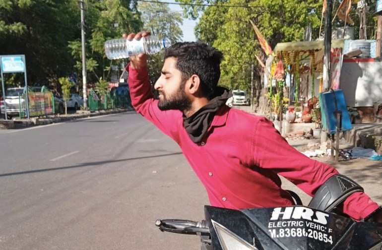 Delivery driver Aman pours water over his head to cool himself after making a delivery [Parthu Venkatesh/Al Jazeera]