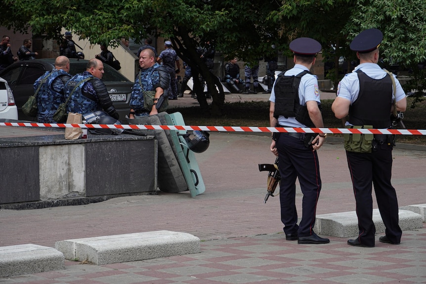 Russian police officers gather behind police tape. 