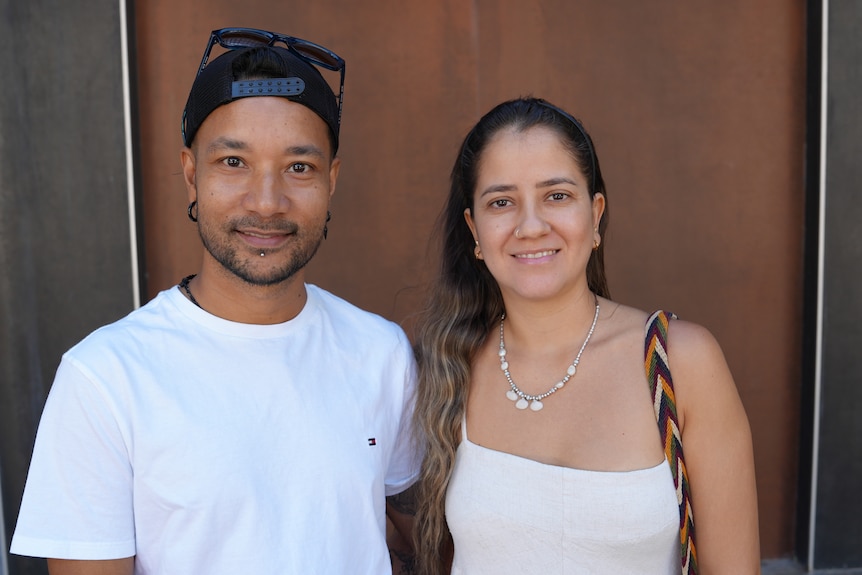 A photo showing a man and a woman standing next to each other with a brown door in the background