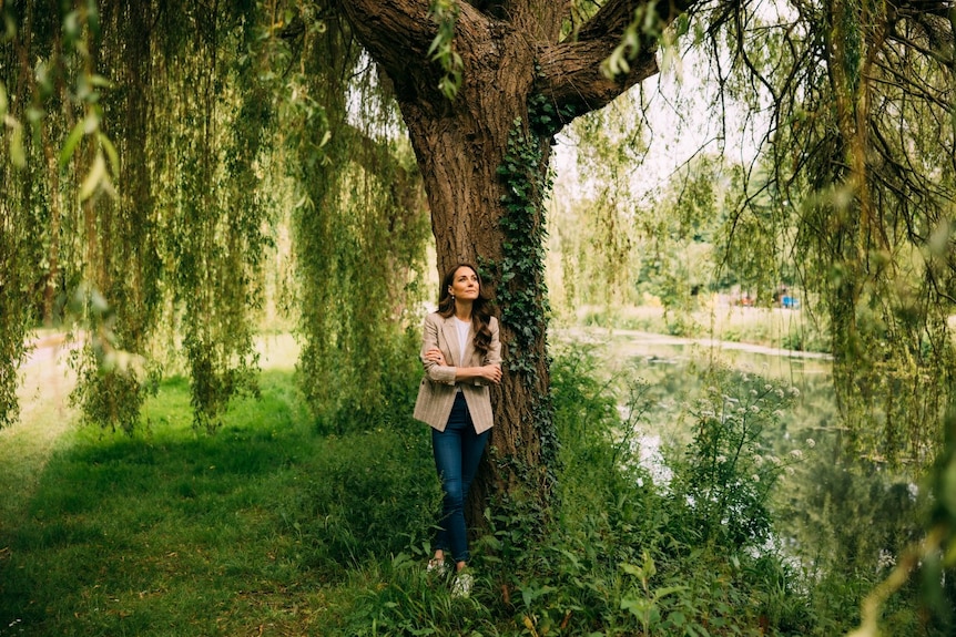 A woman stands underneath a tree, looking up