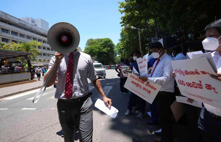 Sri Lankan government doctors protest against the government near the national hospital in Colombo, Sri Lanka, Wednesday, April 6, 2022. For several months, Sri Lankans have endured long lines to buy fuel, cooking gas, foods and medicine, most of which come from abroad. Placards read " No medicines," "Health service is in danger." (AP Photo/Eranga Jayawardena)