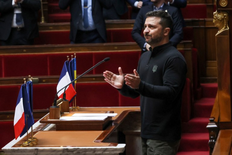 Ukrainian President Volodymyr Zelenskyy applauds after delivering a speech at France's National Assembly