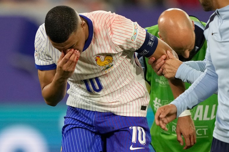 Injured player walks off ground with trainer.