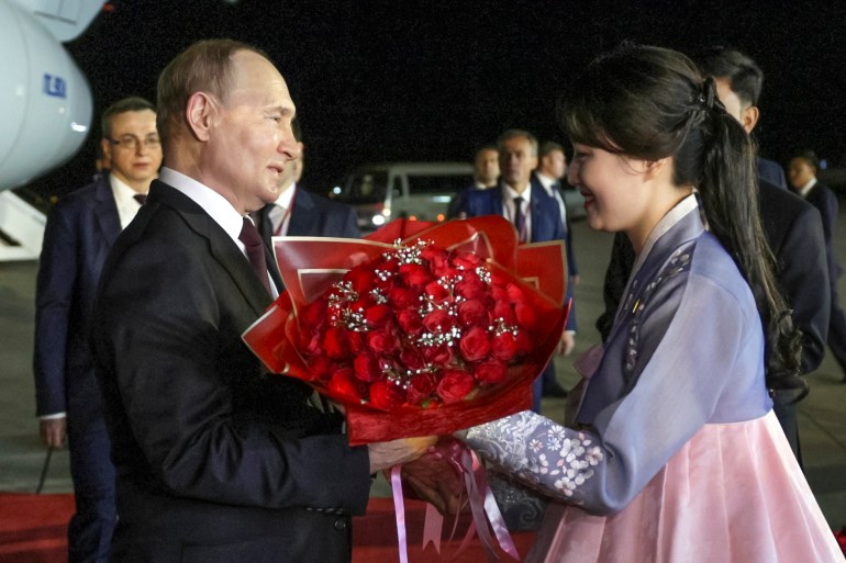 A woman in a traditional Koran hanbok gives Vladimir Putin a bouquet of red roses