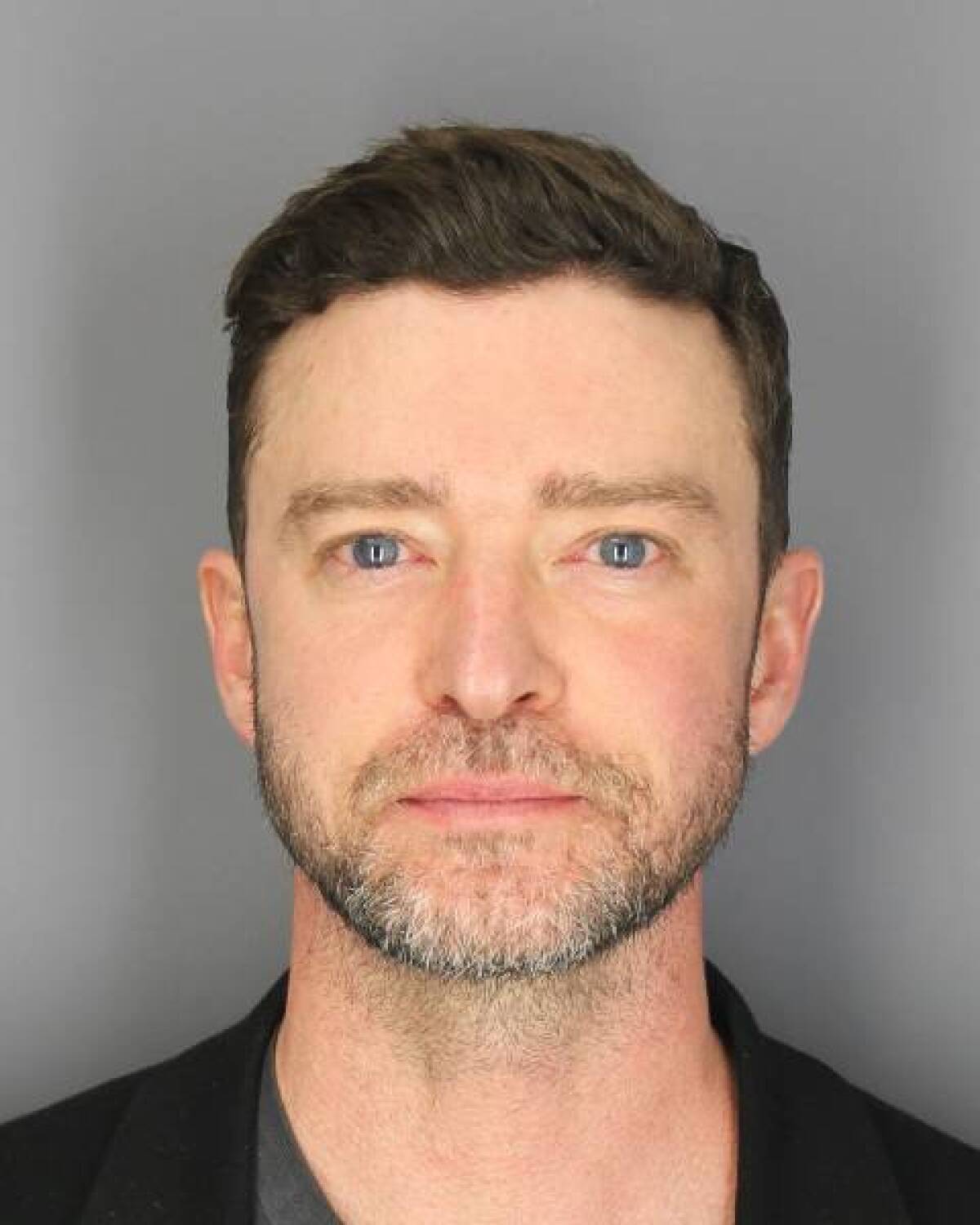 A police mug shot of Justin Timberlake against a light gray background