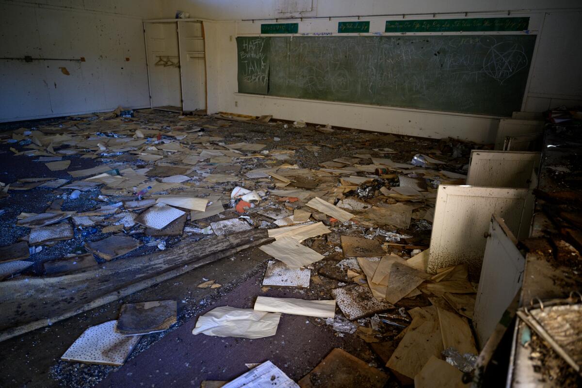 Text books and papers are strewn on the floor in a large classroom