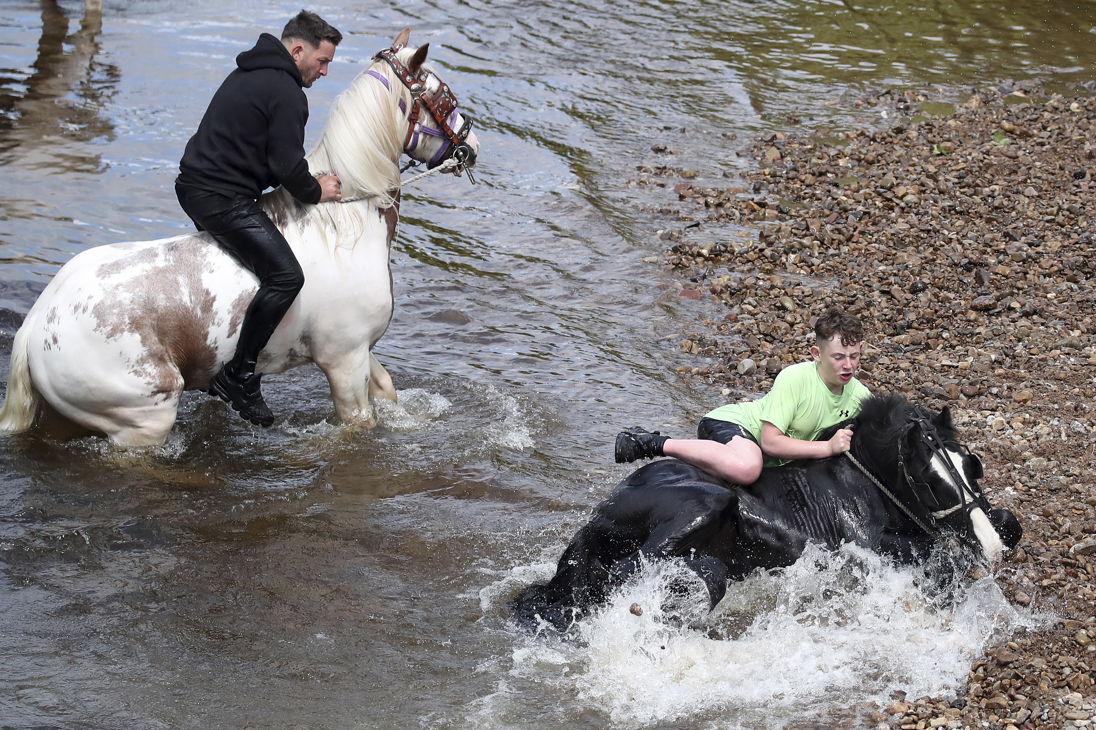 Riders take their horses through the river at the Appleby Horse Fair