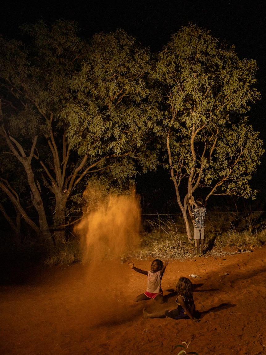 A girl throws up dirt into the air 