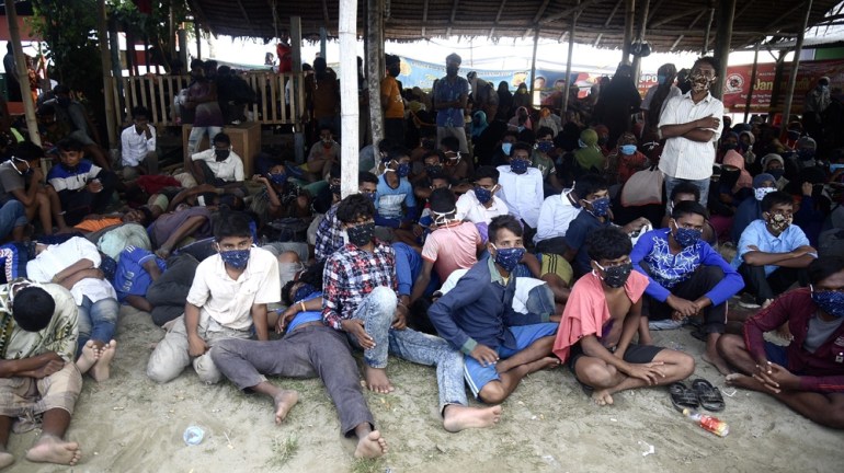 Rohingya refugees sitting beneath a shelter after arriving in Aceh in Sept 2020. They look tired and thin. They are barefoot