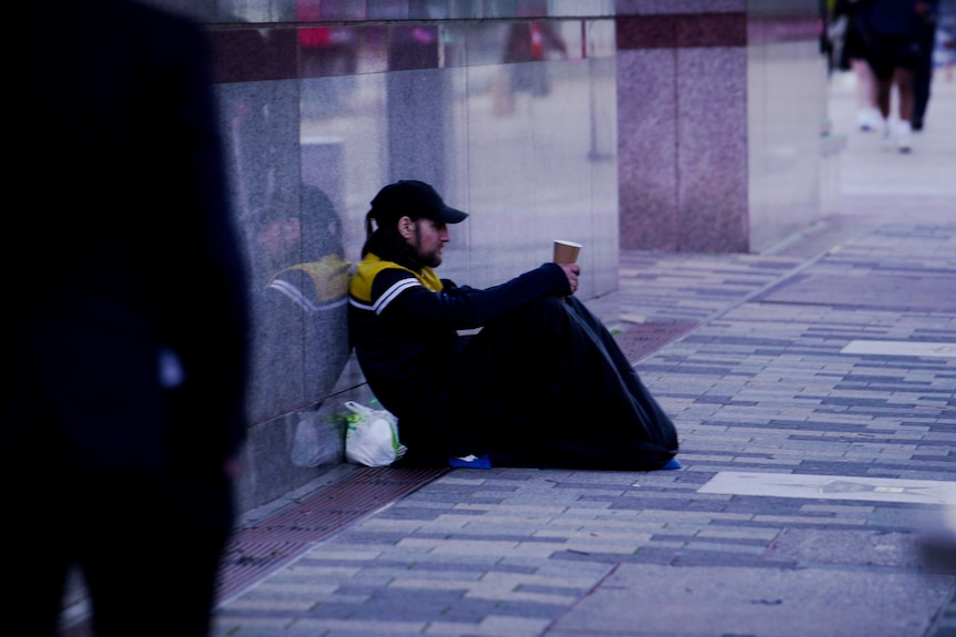 A man sits and asks for money