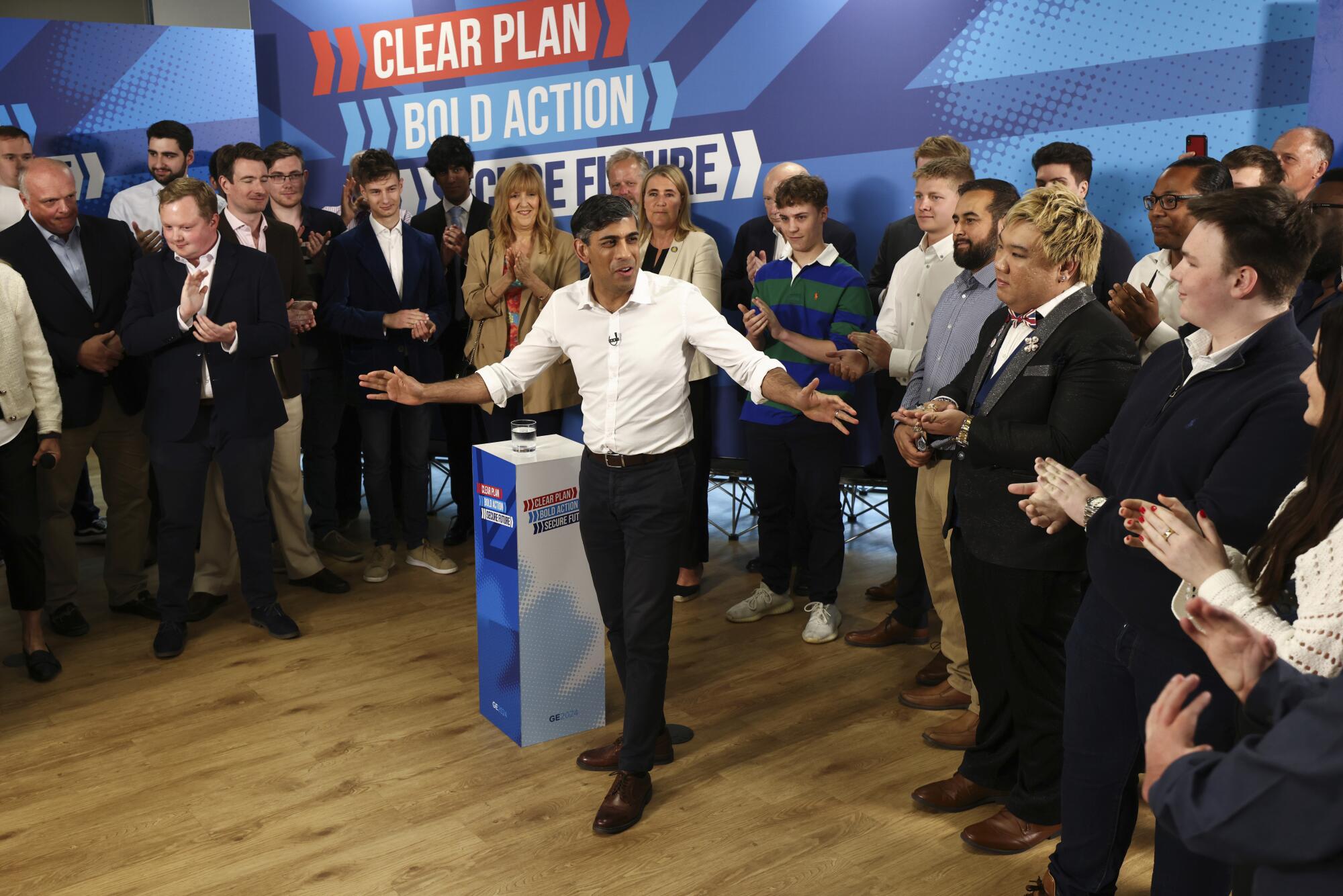 British Prime Minister Rishi Sunak gestures as people around him clap.