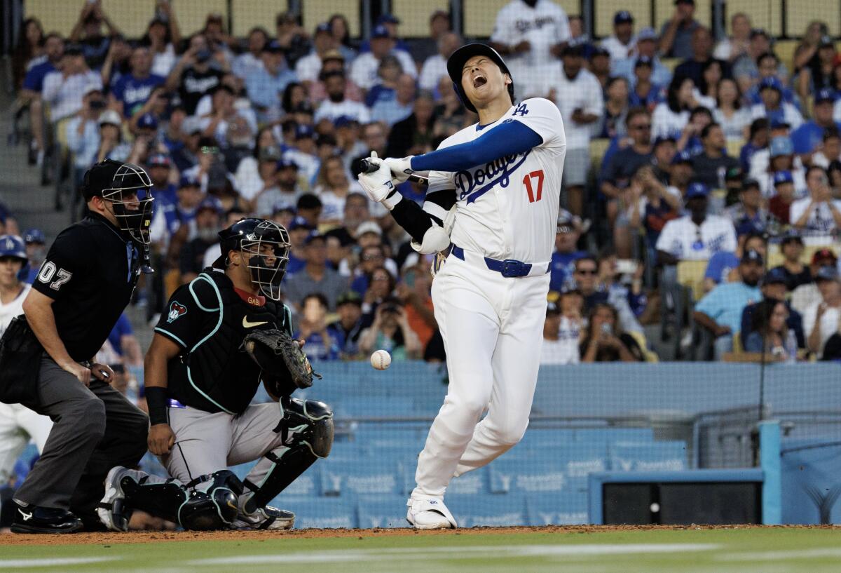Dodgers designated player Shohei Ohtanilets out a scream as he foul tips a ball off his leg