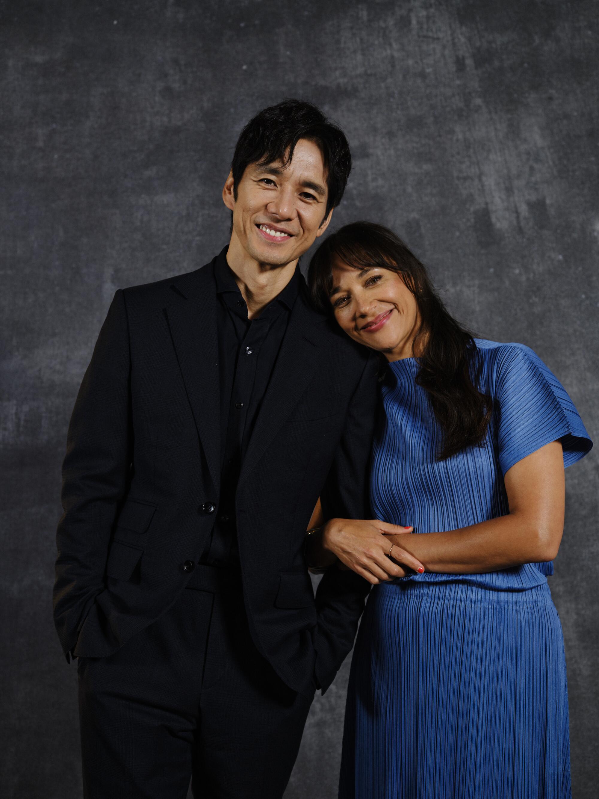 A man in a dark suit leaning toward a woman in a blue dress.