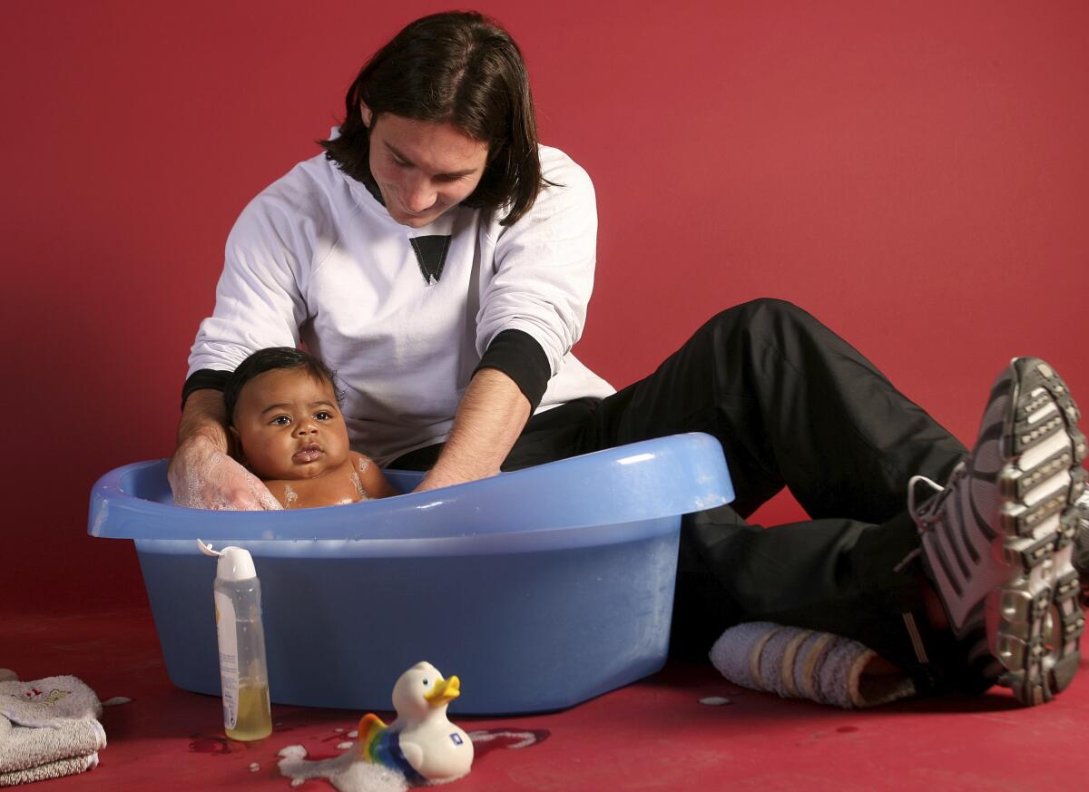 This photo taken in September 2007 shows a 20-year-old Lionel Messi helping to bathe a 6-month-old Lamine Yamal