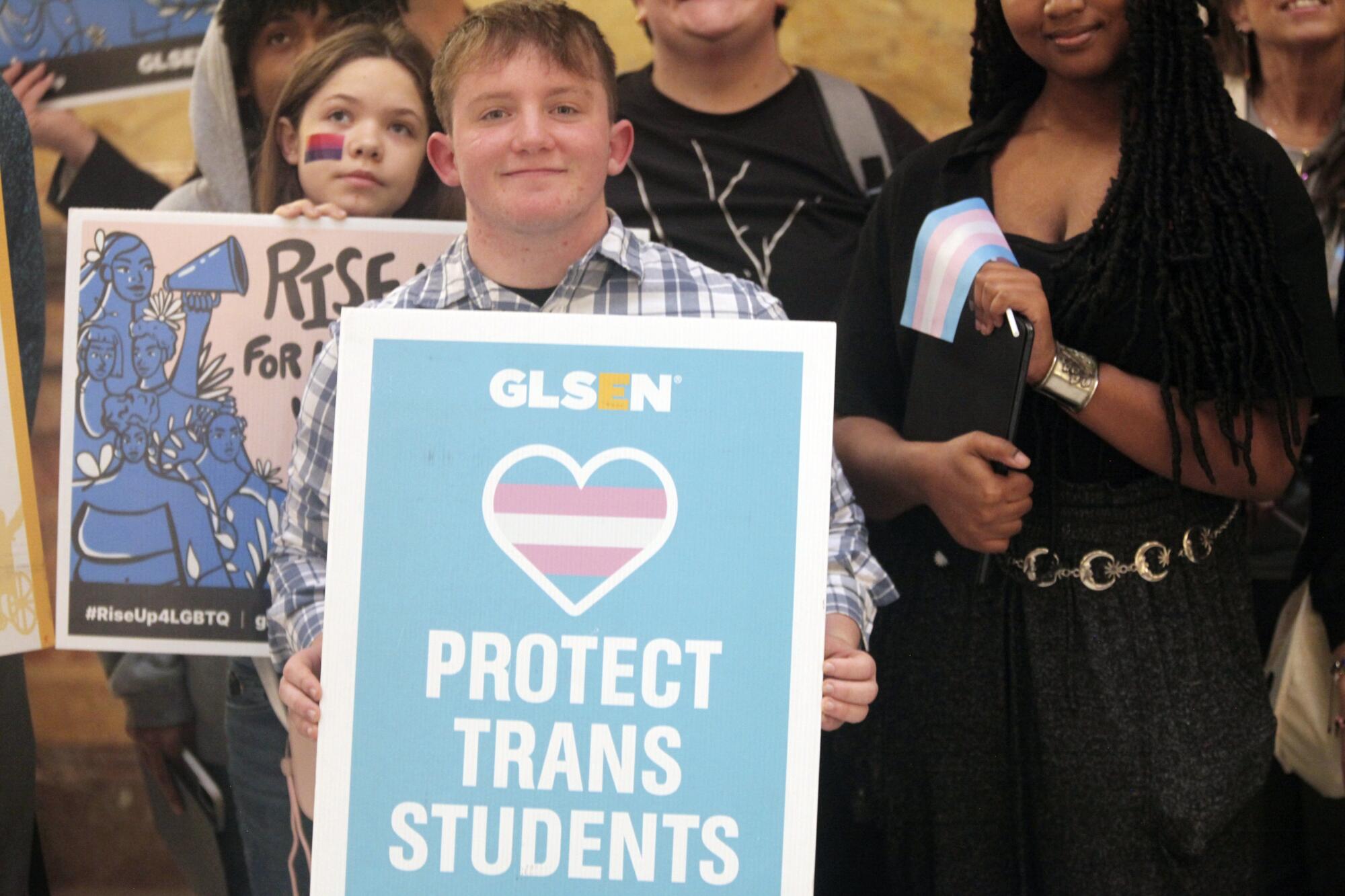 A person holds a sign that says "Protect trans students."