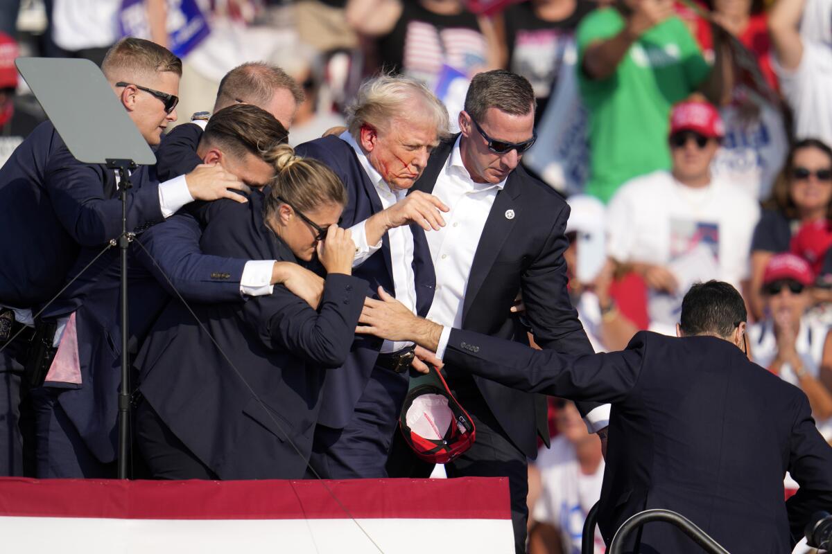 Former President Trump is helped off stage at a campaign rally on Saturday in Butler, Pa.