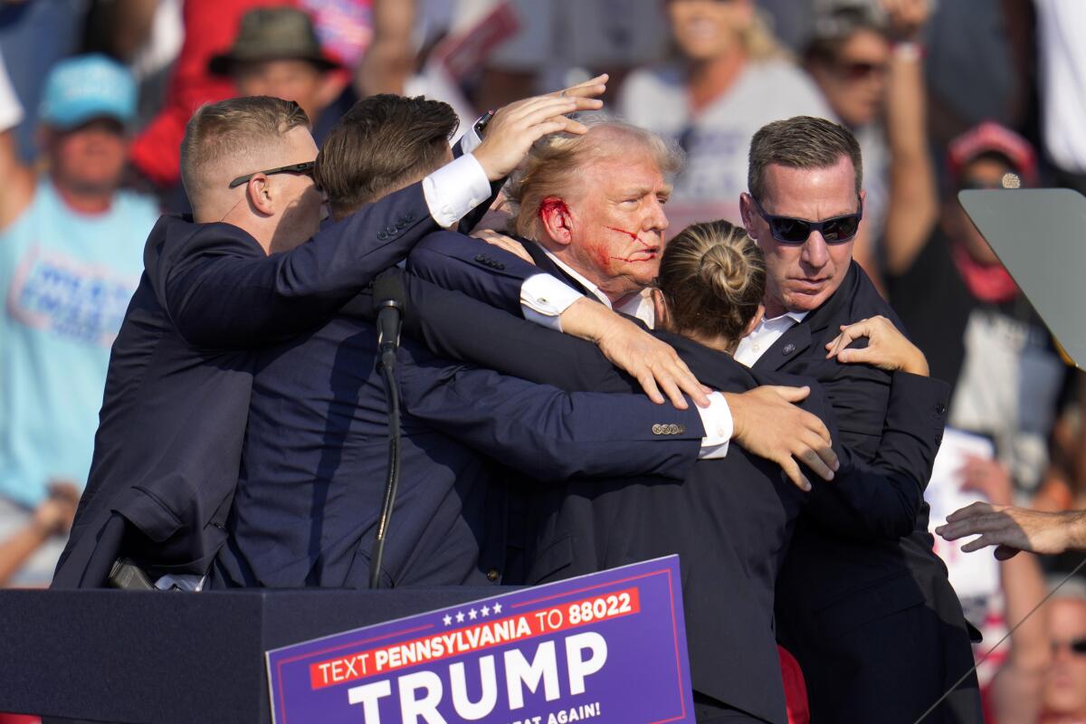 Donald Trump with blood on his face surrounded by secret service agents 