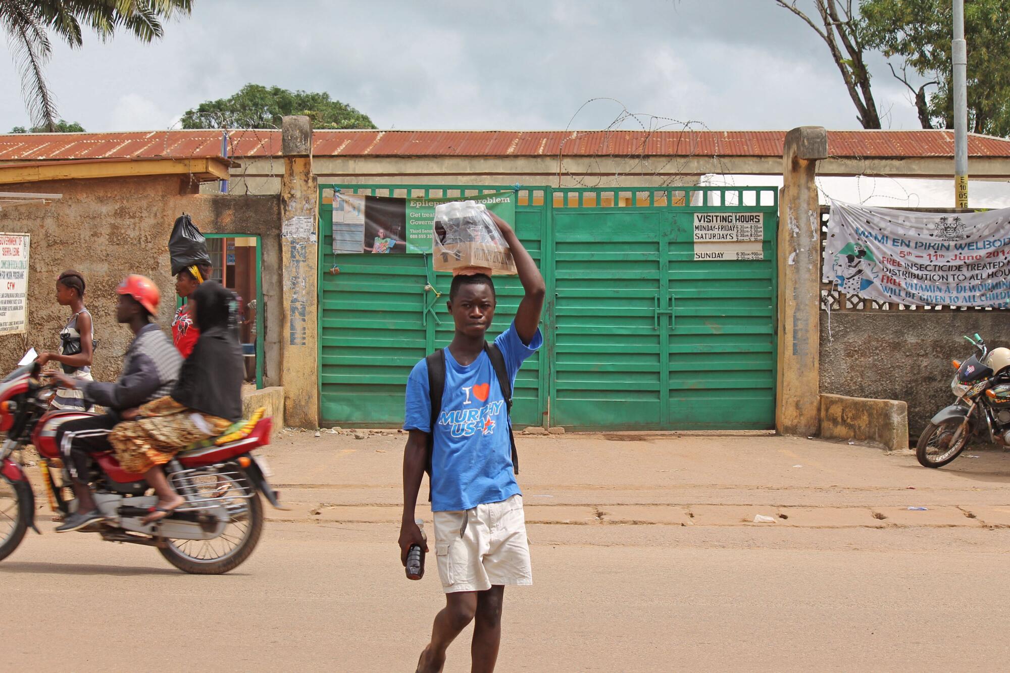 A boy selling soft drinks walks past a clinic