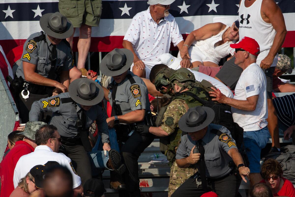 A person is removed by state police from the stands at a rally.