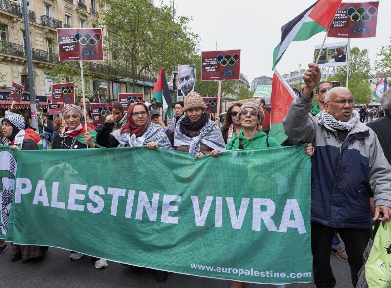 People holding a banner reading "Palestine will live" protest Israel being allowed to take part in the 2024 Olympic Games.