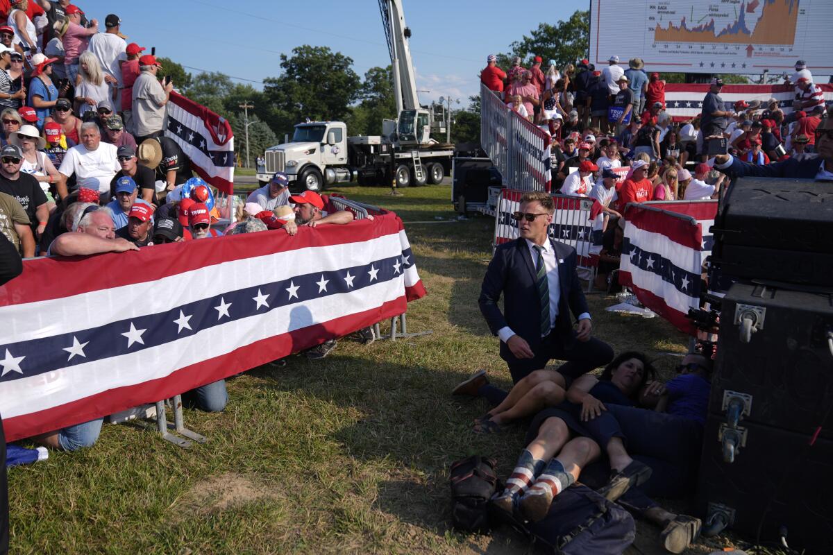 People scramble near red, white and blue banners with stars 