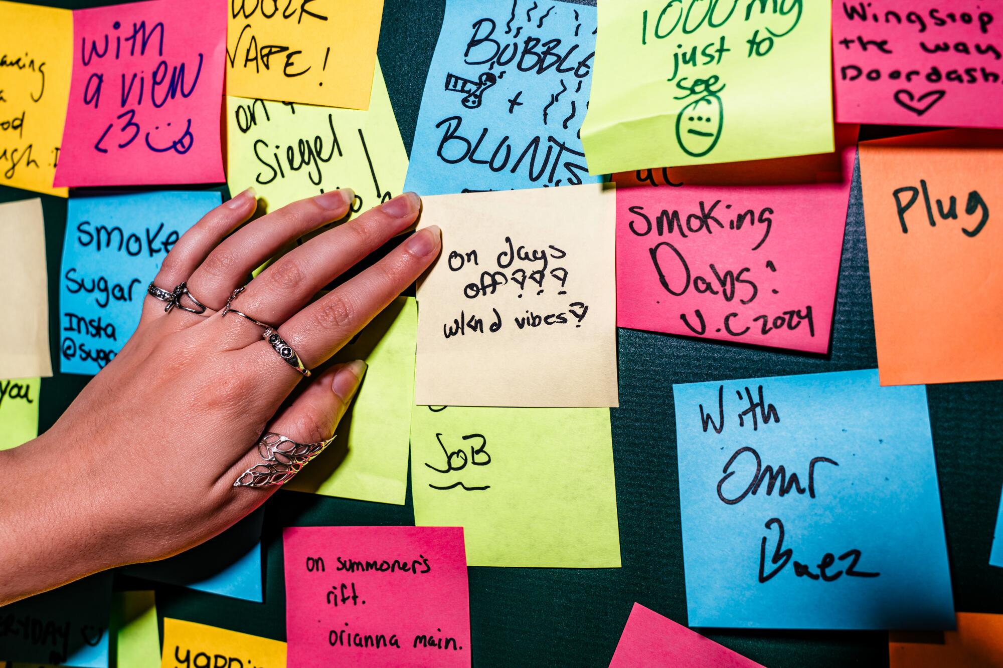 A hand against a wall of colorful sticky notes