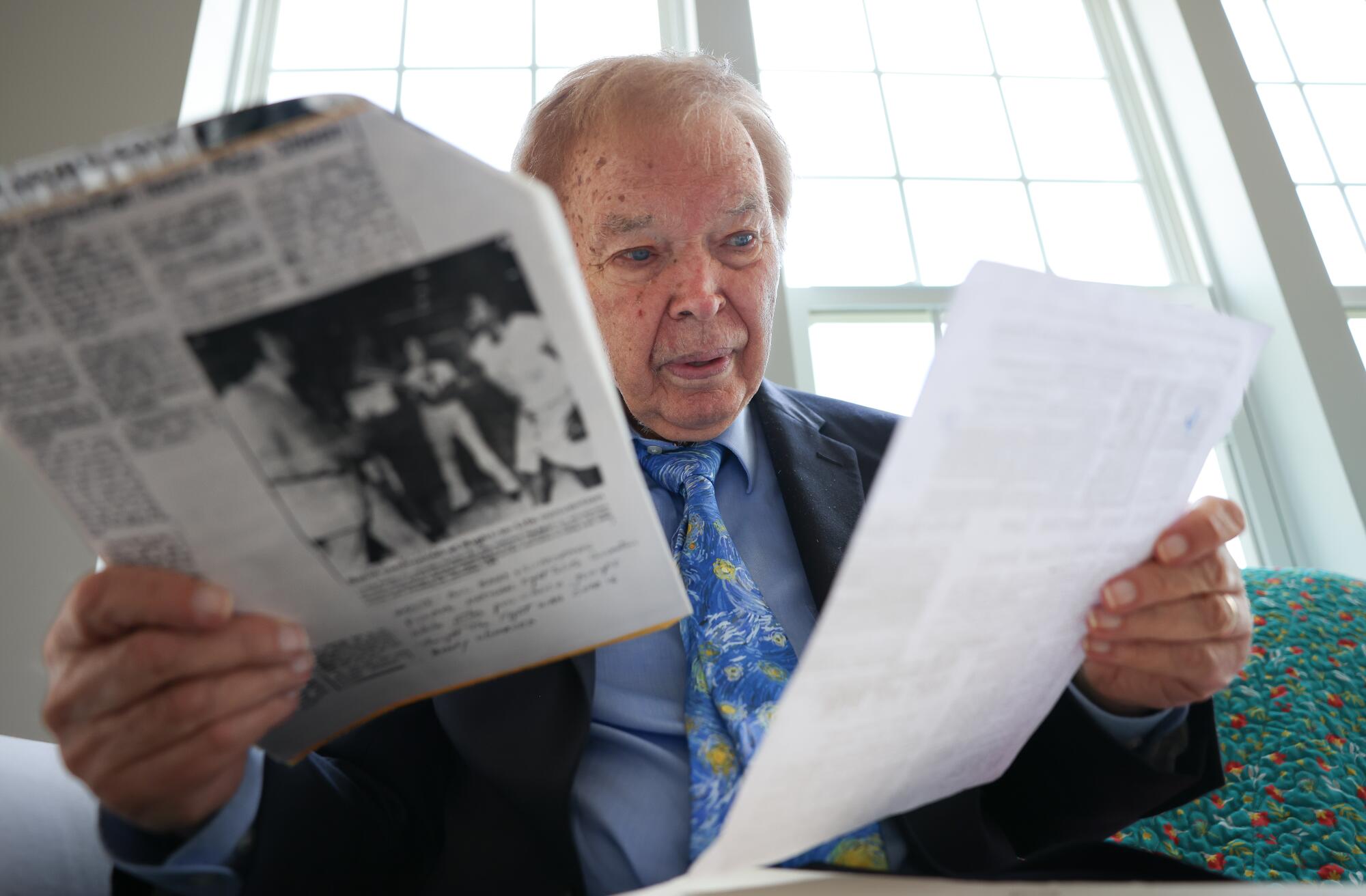 A man holds up papers in each hand.