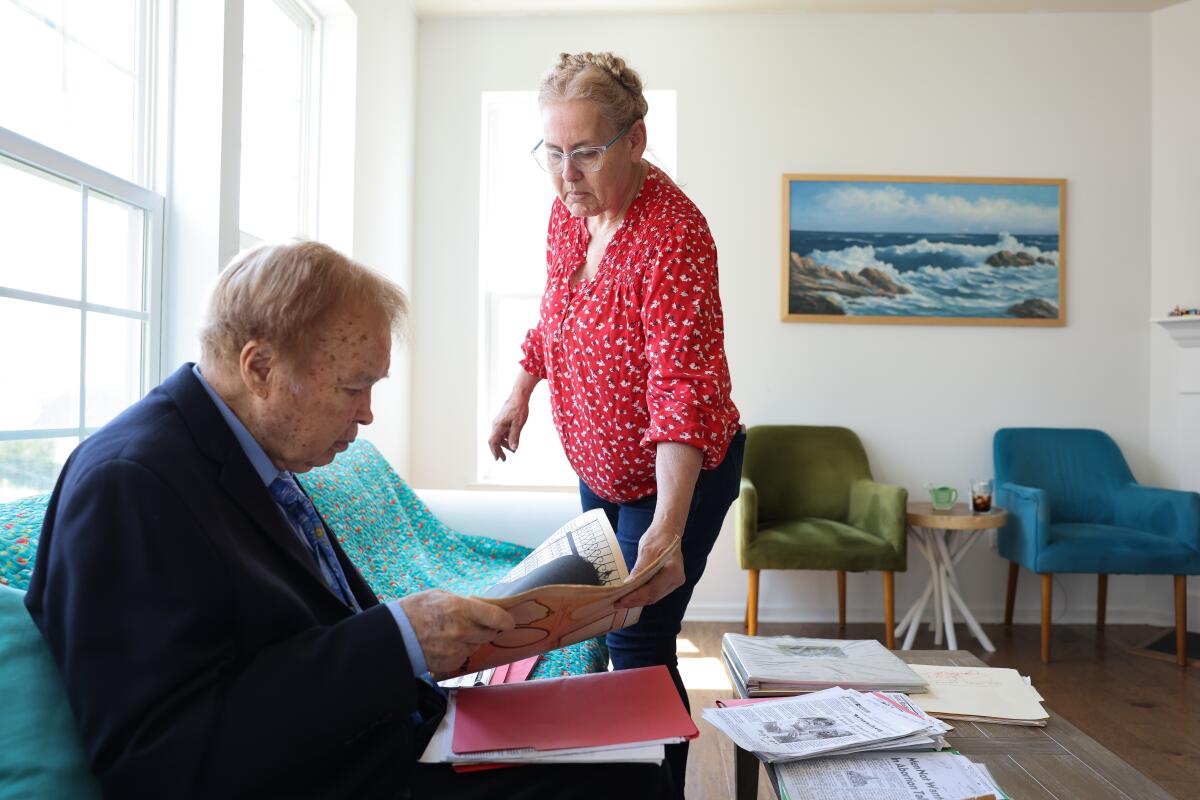 Bill Baird and his wife Joni Baird look through articles written about him.