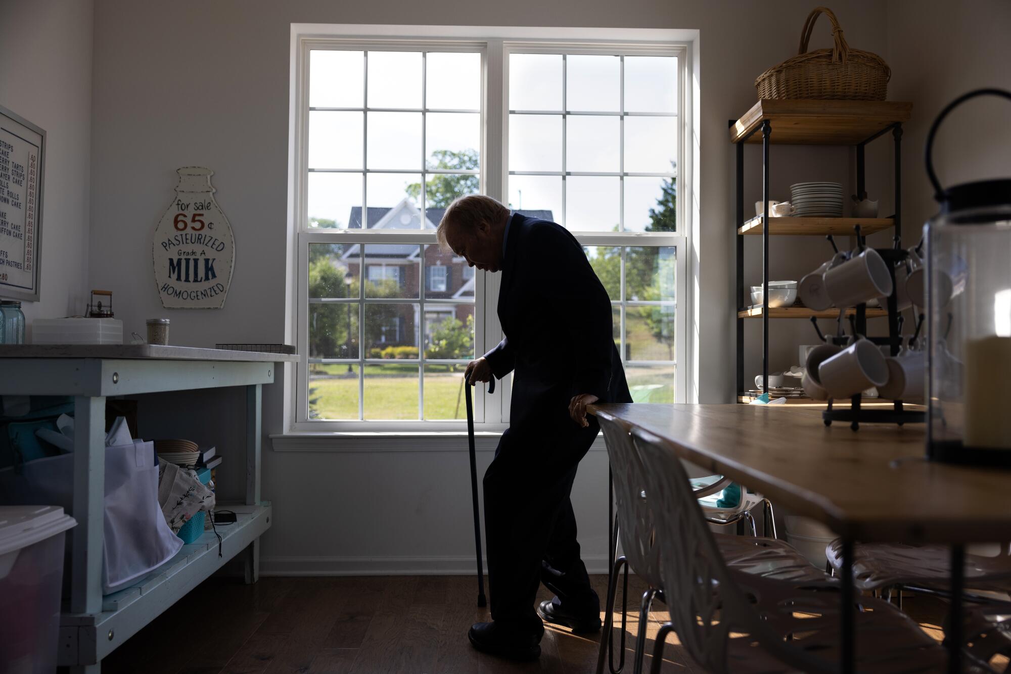 A man leans on a cane in a room.