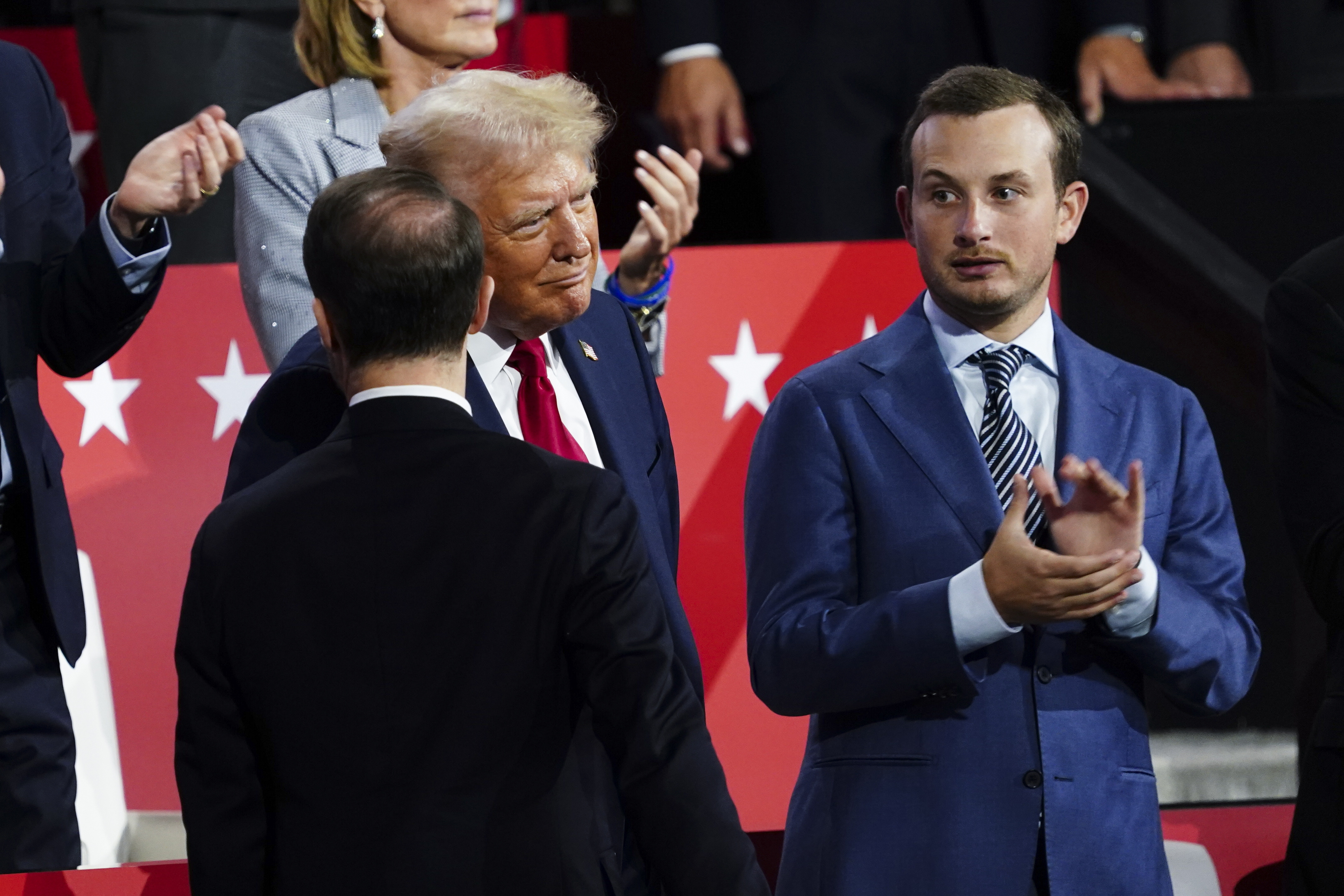 Republican presidential nominee and former President Donald J. Trump (C) receives a message from an aide