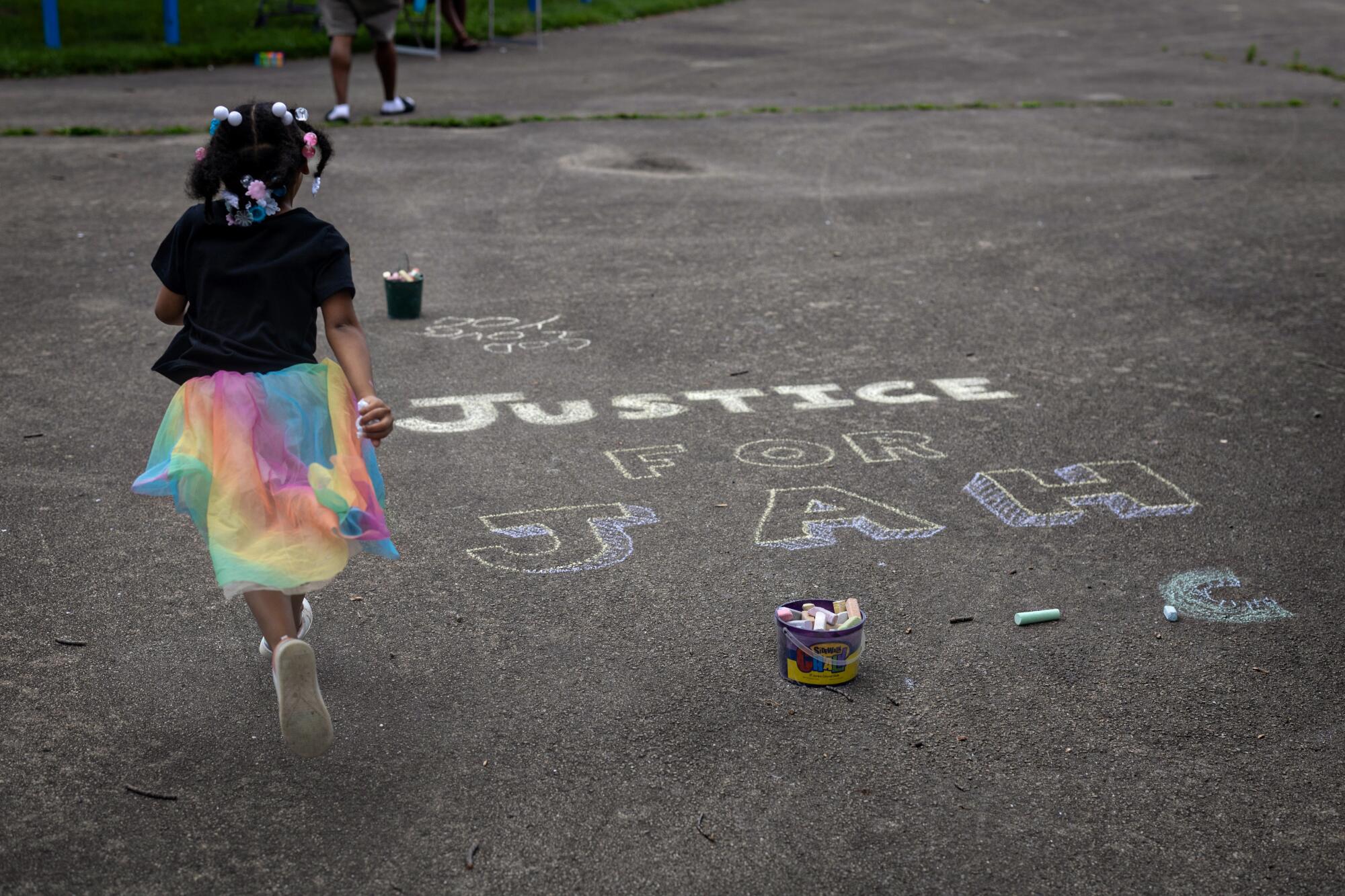 A child runs past the phrase "Justice for Jah" — a reference to Samuel Sharpe Jr., who was killed by police in Milwaukee.