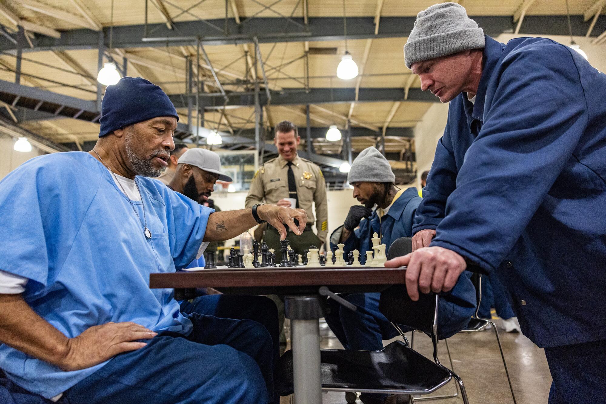 Prisoners study a chess board.  