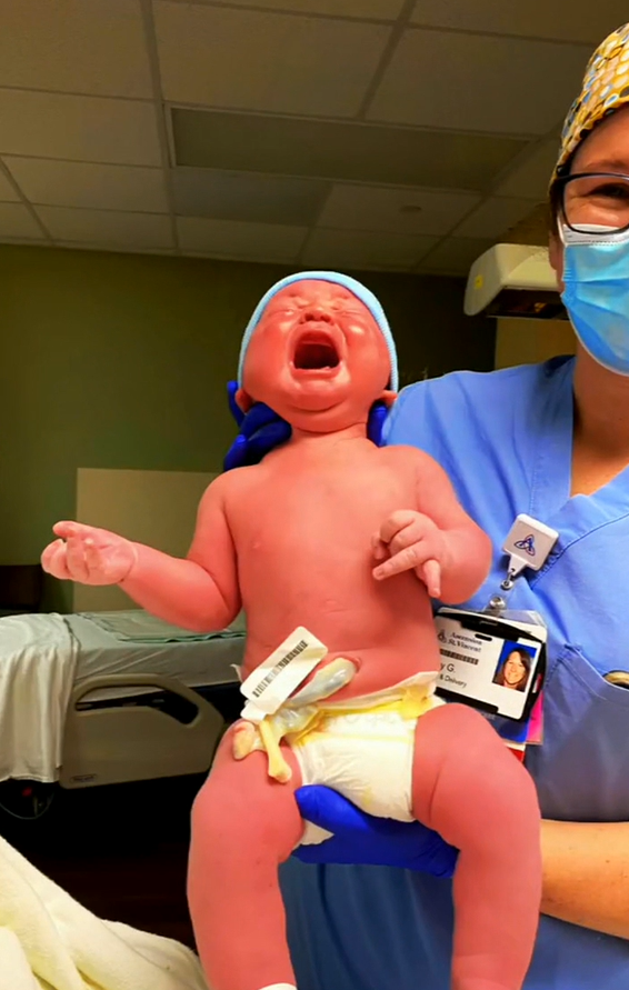 A delivery room worker held up the 12lb 6oz baby shortly after he was delivered via C-section