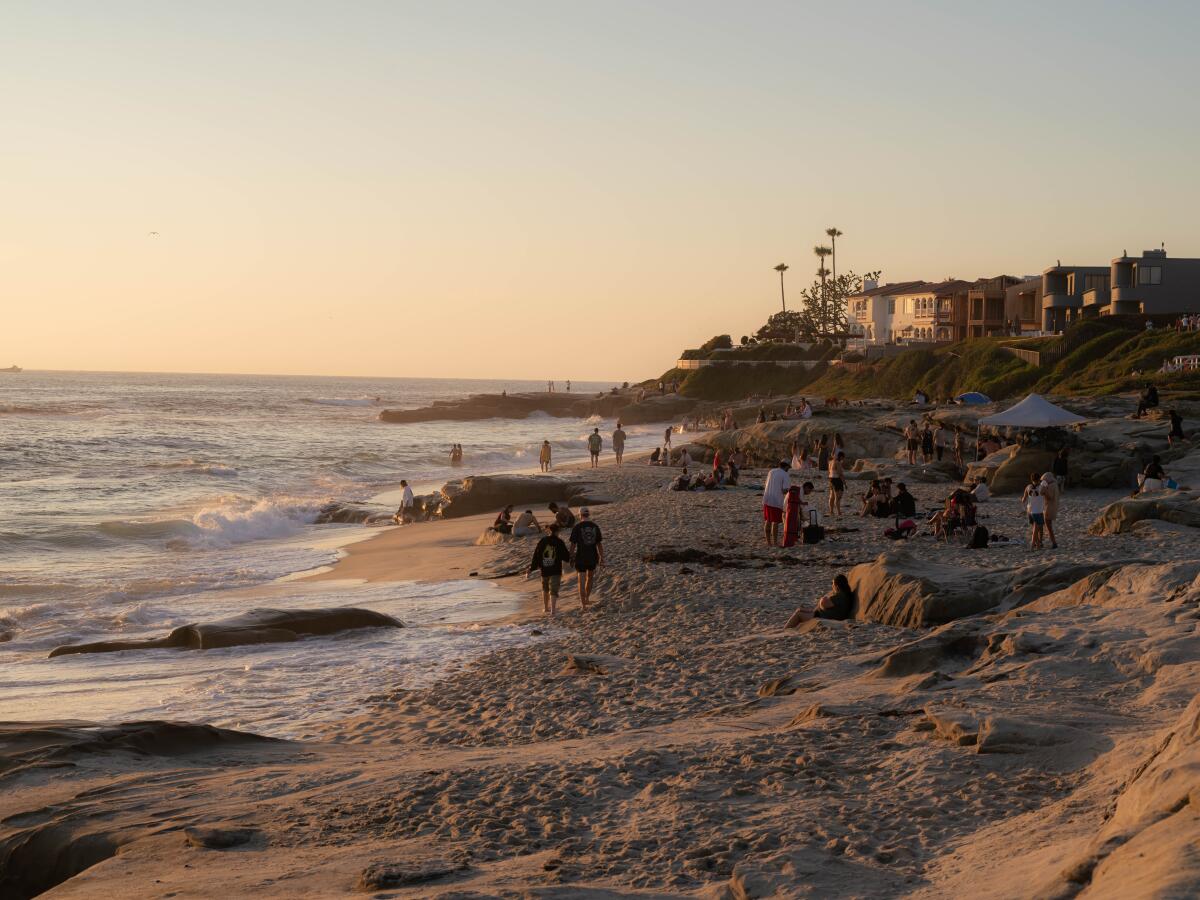 People walk on the beach at sunset