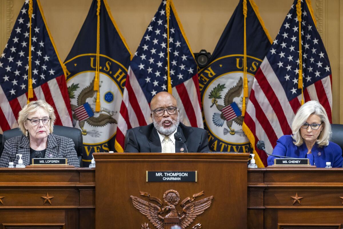 A man sits in the House of Representatives while flanked by two women.