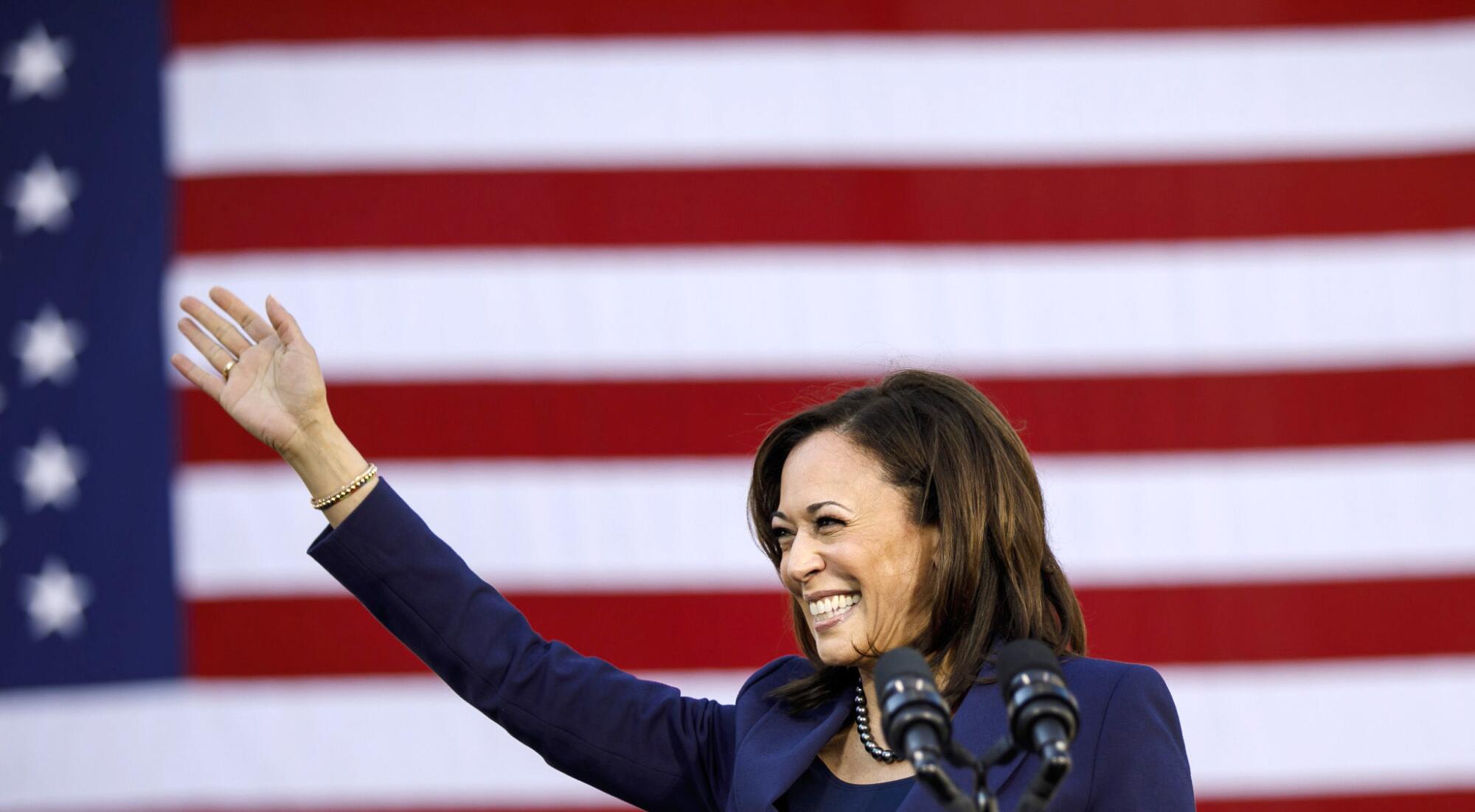 Sen. Kamala Harris waves in front of a U.S. flag.