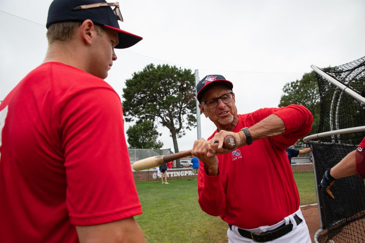 Manager Scott Pickler, right, demonstrates his bat grip to a player before a Cape Cod League game.