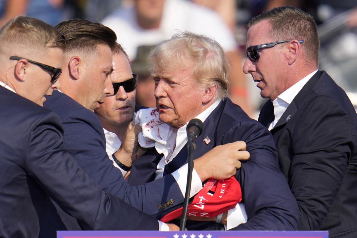 Former President Donald Trump is helped off the stage at a campaign event in Butler, Pa., after being shot.