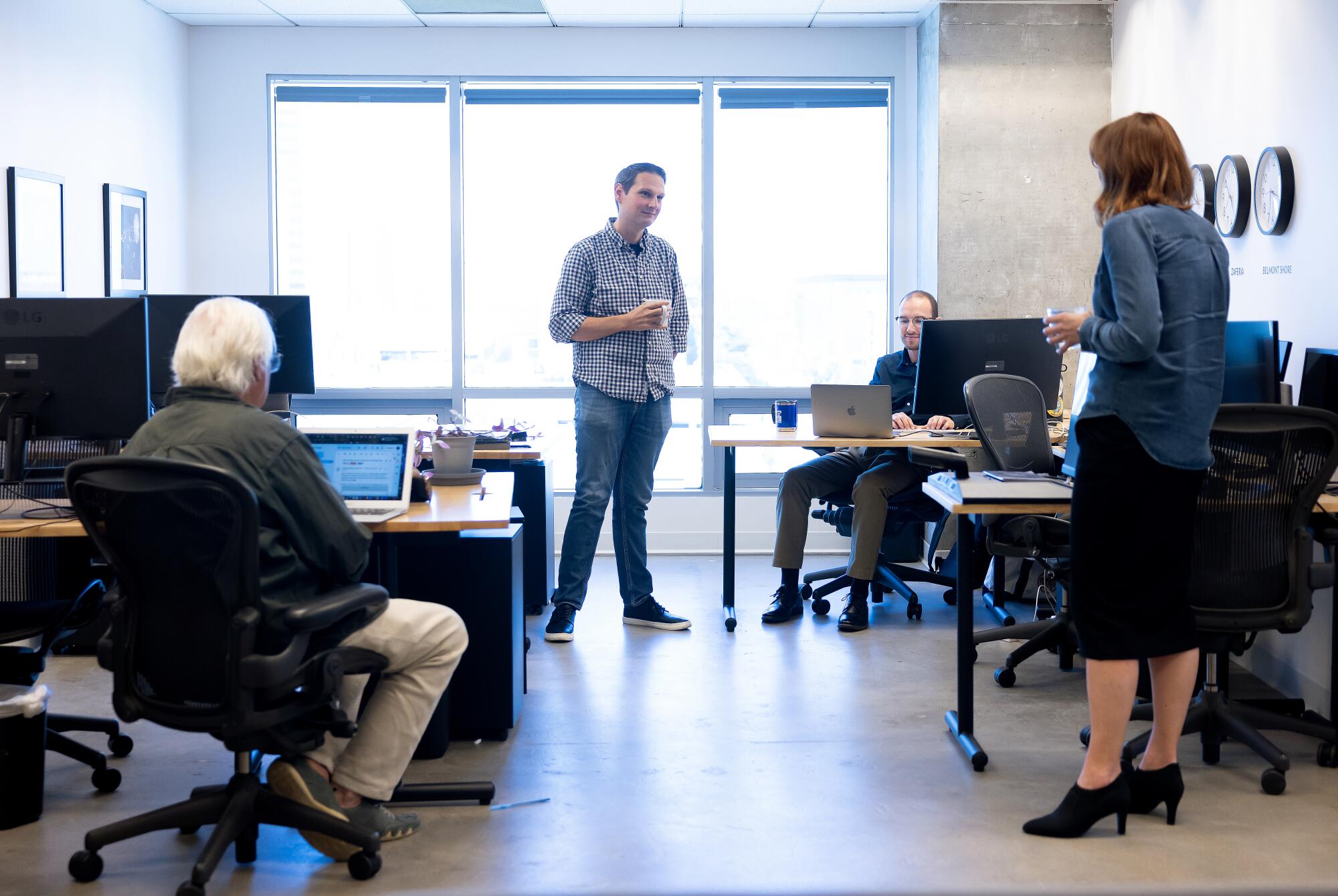 People, some seated, some standing, in an office.