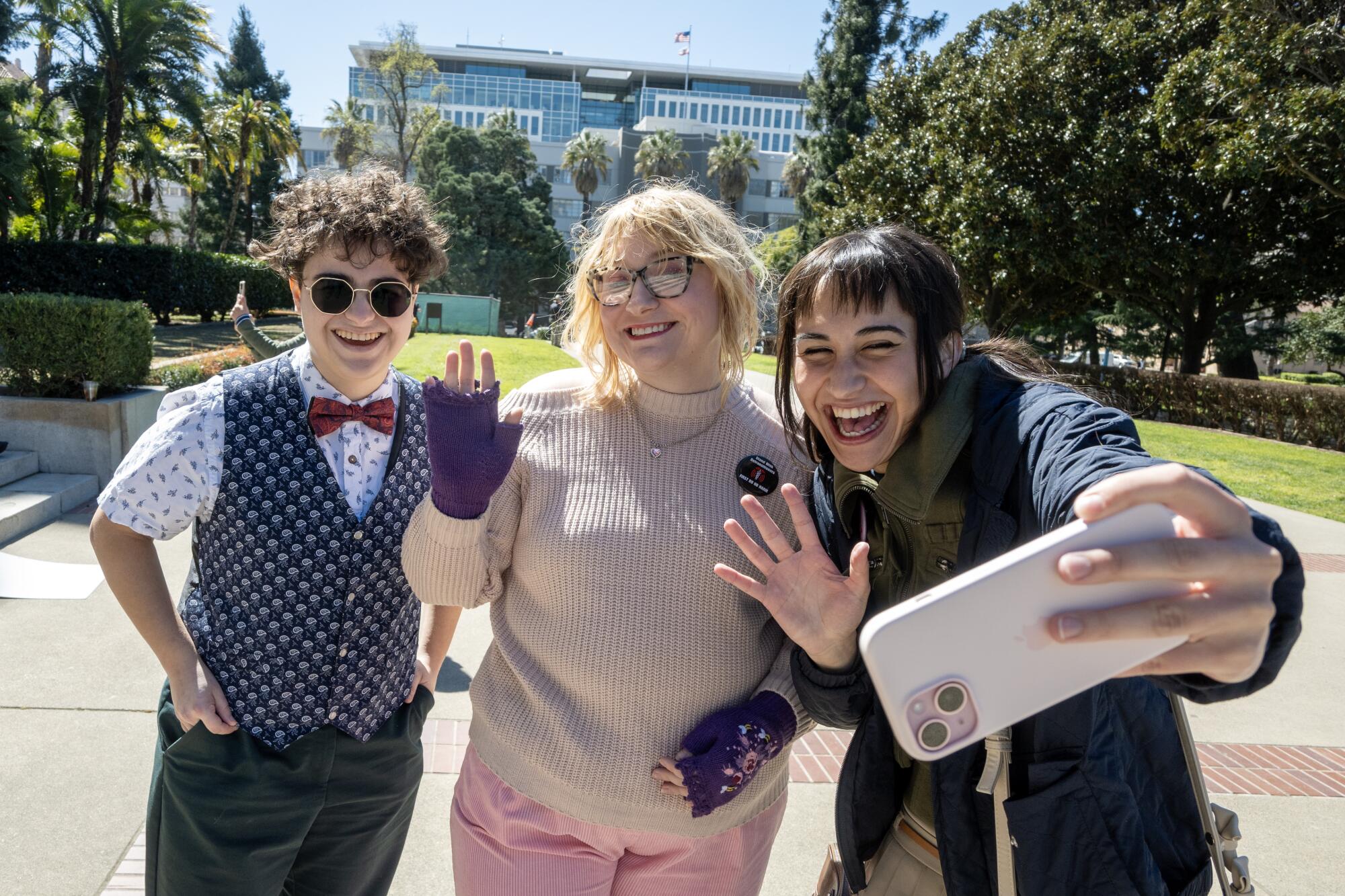 Chloe Cole takes a selfie with two other people