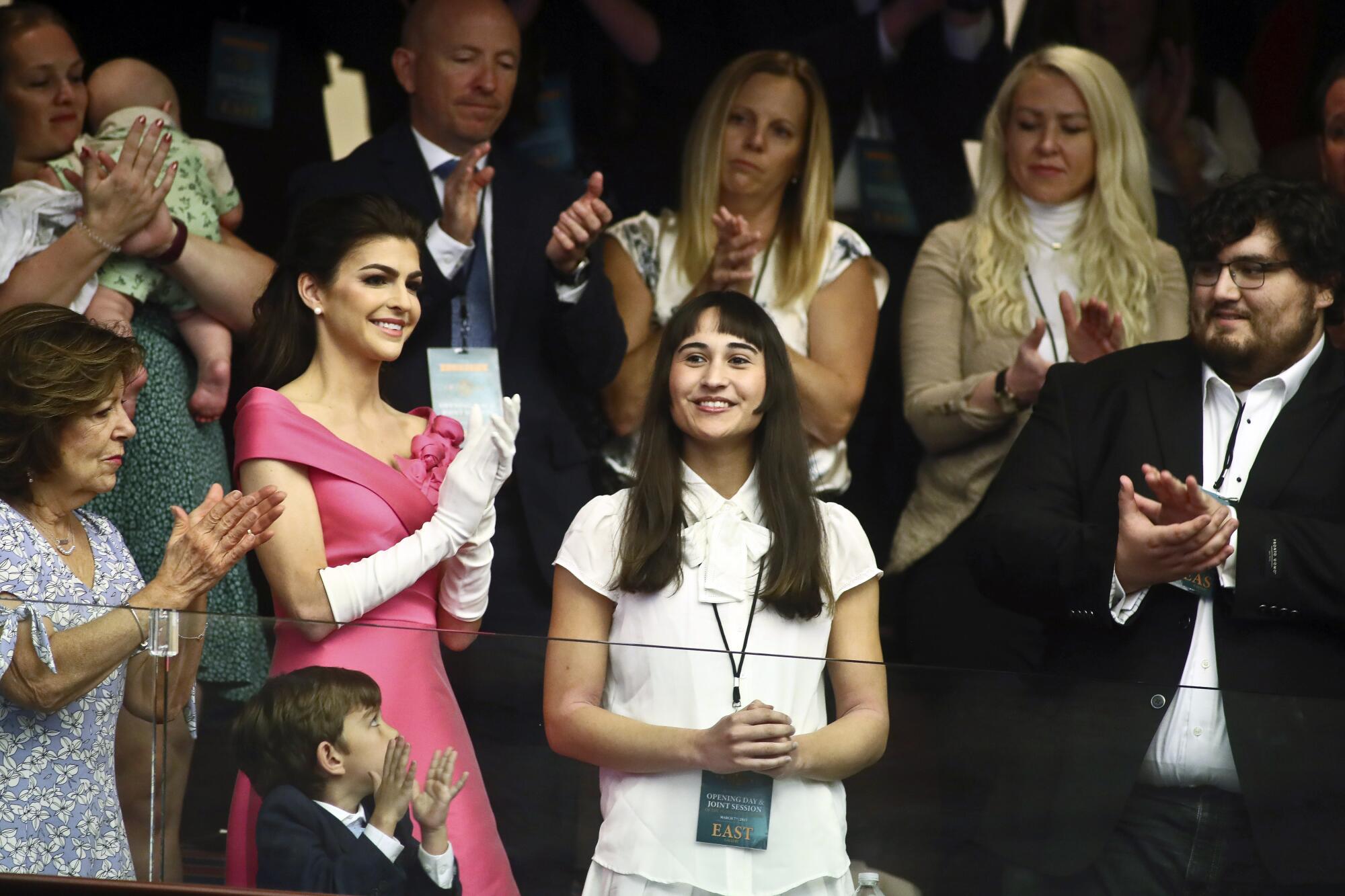 Chloe Cole stands in a crowd as others around her applaud