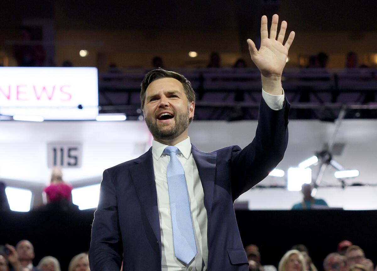 A man stands with his arm in the air, waving at people