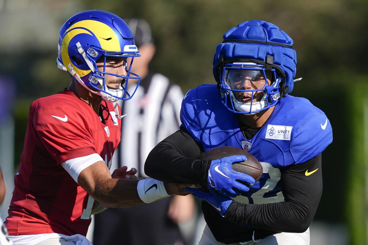 Rams quarterback Jimmy Garoppolo hands off the football Blake Corum during camp practice Monday. 